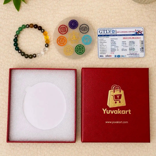 Bracelet, colorful circular object, and Yuvakart box on a beige surface with a candle and green leaves.
